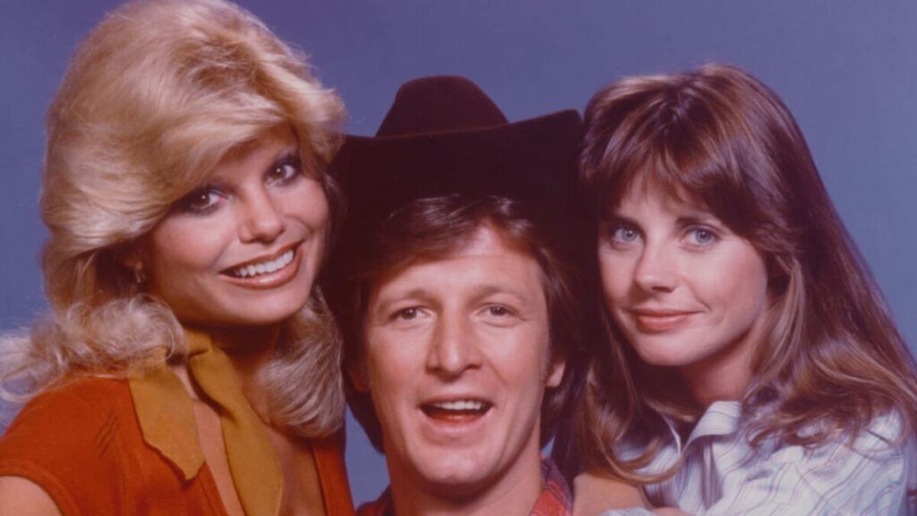 Loni Anderson posing with WKRP in Cincinnati castmates during a promotional photo shoot, showcasing the iconic sitcom’s ensemble from the late 1970s.