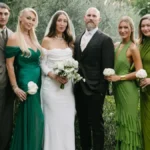 Close-up of Alana Hadid standing arm in arm with her sibling at a marriage celebration, both wearing coordinated outfits.