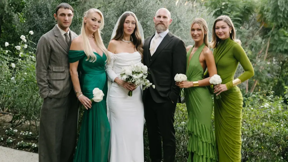 Close-up of Alana Hadid standing arm in arm with her sibling at a marriage celebration, both wearing coordinated outfits.