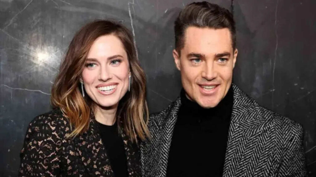Allison Williams and Alexander Dreymon attending a film premiere, Williams in a shimmering dress and Dreymon in a tuxedo, cameras flashing behind them.