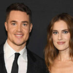 Allison Williams and Alexander Dreymon standing side by side, smiling warmly, Allison in an elegant white dress and Alexander in a tailored suit, confirming their marriage.