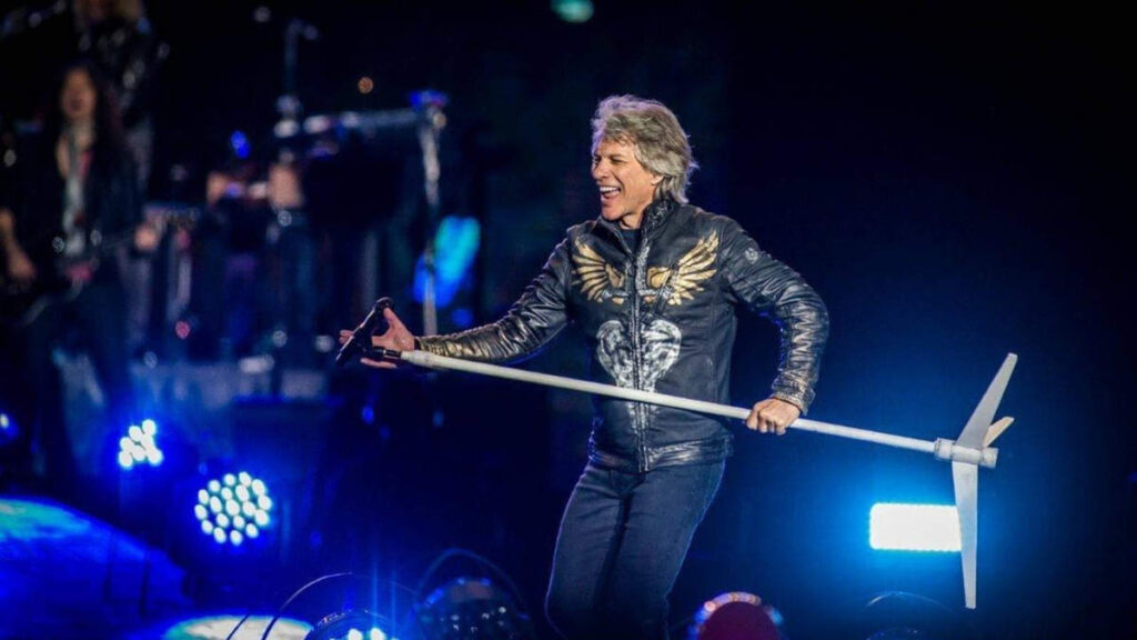 Jon Bon Jovi performing on stage after recovering from lung cancer surgery, holding the microphone with renewed energy under bright concert lights.