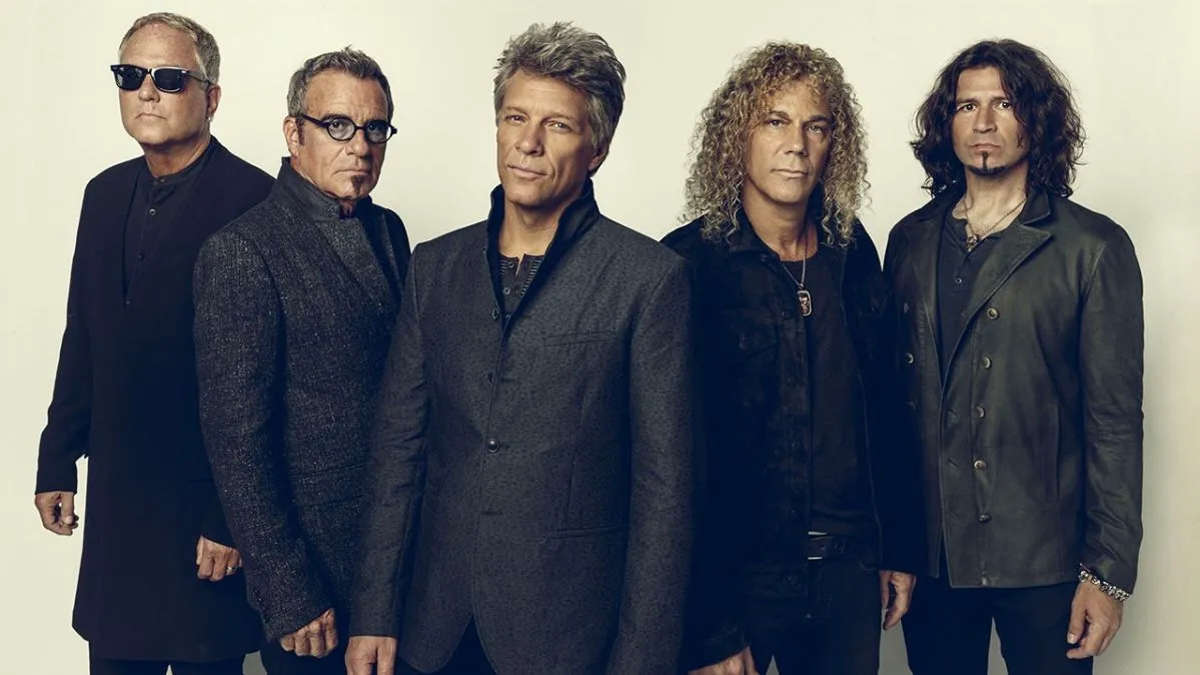 Poster image showing Jon Bon Jovi in leather jacket holding a microphone, text overlay reads ‘Bon Jovi: The Triumphant Tour Return.