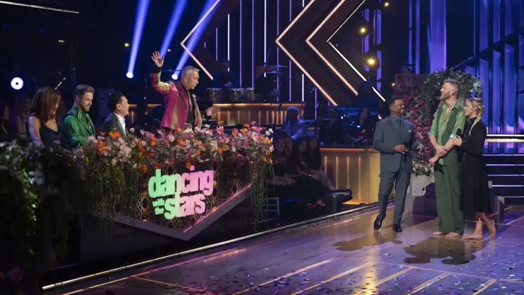 A ballroom lit in emerald-green hues, couples in formal dancewear take the floor, glittering backdrop reads ‘Wicked Night’ as the judges watch.