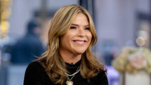 Jenna Bush Hager smiling and sitting at the Today show desk, wearing a professional outfit, as she engages with co-hosts during a live broadcast.