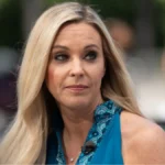 Kate Gosselin smiling at the camera, wearing a light-colored blouse with her signature blonde layered hairstyle.