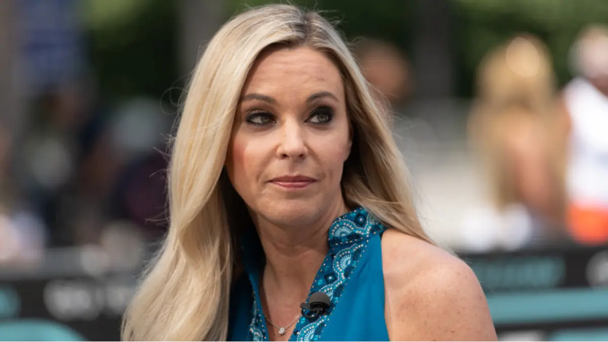 Kate Gosselin smiling at the camera, wearing a light-colored blouse with her signature blonde layered hairstyle.