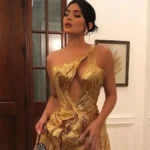 Kylie Jenner posing on the red carpet in a shimmering gold gown, fitted silhouette with a dramatic train and sleek hairstyle.