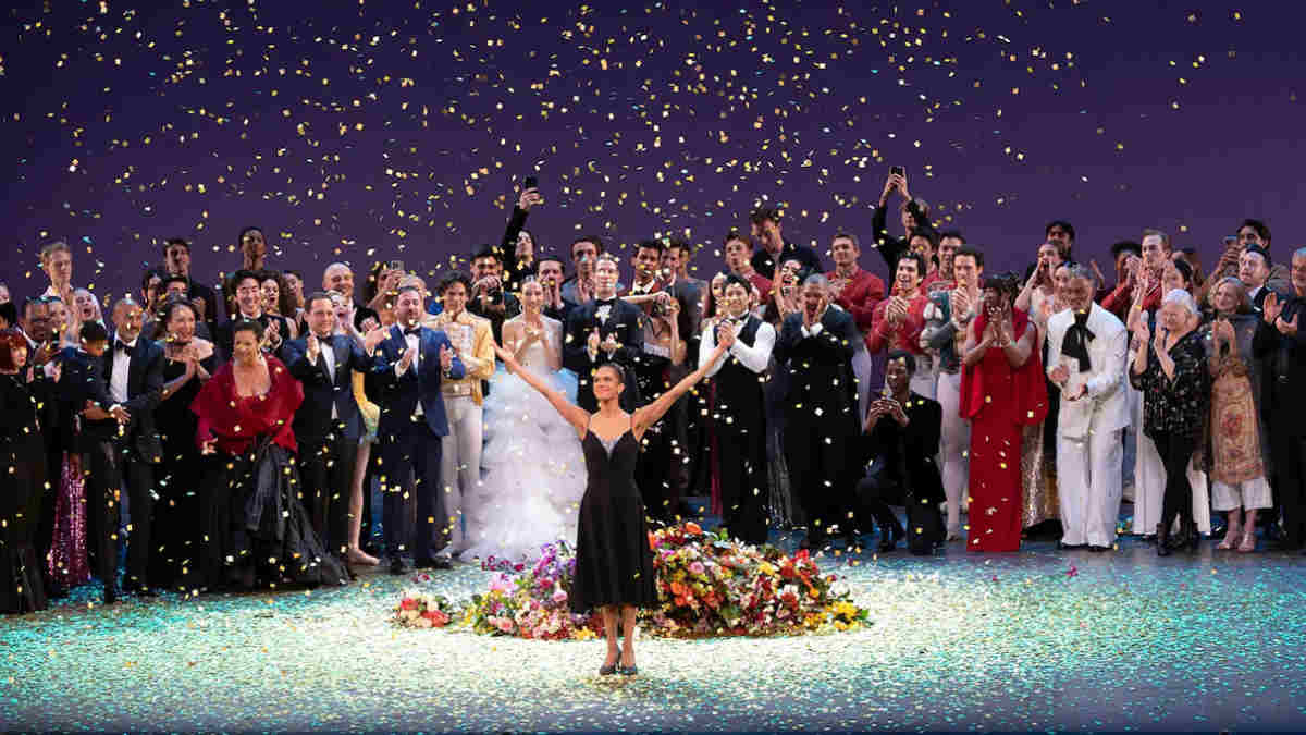 Misty Copeland standing on stage with her family, all smiling and posing together after her performance, with applause from the audience in the background.