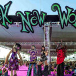 Wide shot of the Sick New World festival grounds in Las Vegas, massive crowd in front of a main stage lit with red and purple lights.