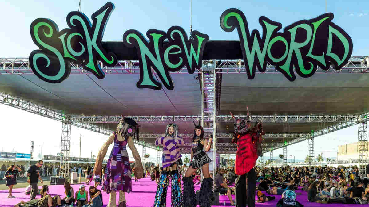 Wide shot of the Sick New World festival grounds in Las Vegas, massive crowd in front of a main stage lit with red and purple lights.